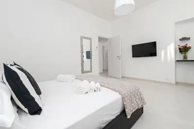 a white bedroom with a bed with two shoes on it at White Flat Termini in Rome