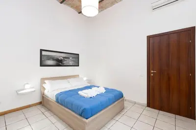 a bedroom with a bed with blue sheets and white pillows at San Pietro Terrace Apartment in Rome