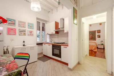 a kitchen with white cabinets and a bed in a room at Artistic colorful Apart Vatican Museums in Rome