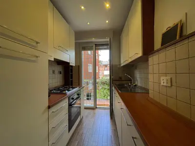 a kitchen with white cabinets and a wooden floor at Appiano Garden Apartment in Rome