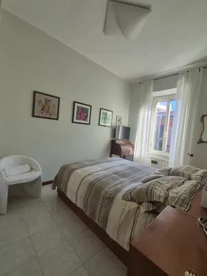 a bedroom with a bed and a chair and a window at La casa di Giulia in Rome