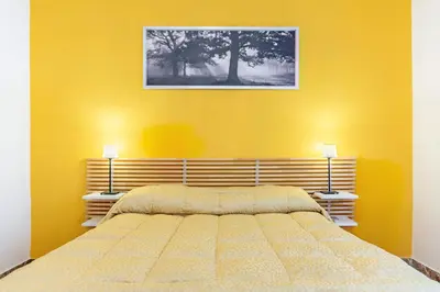 a yellow bedroom with a bed and two lamps at 10 Minutes by Car from St Peter's Basilica in Rome