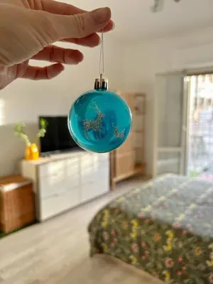 a hand holding a blue ornament with a bed at Wood Apartment - Rome Battistini in Rome