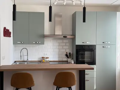 a kitchen with white cabinets and a counter with two chairs at Dolce Roma Apartment in Rome
