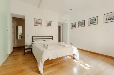a white bedroom with a bed and a wooden floor at Happy Home in Rome