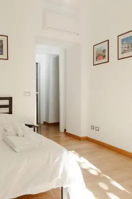 a white bedroom with a bed and a wooden floor at Happy Home in Rome
