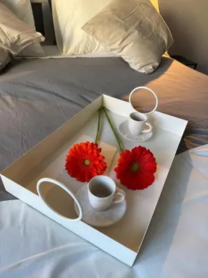 a tray with two cups and flowers on a bed at Guest House VB Luxury Suites in Rome