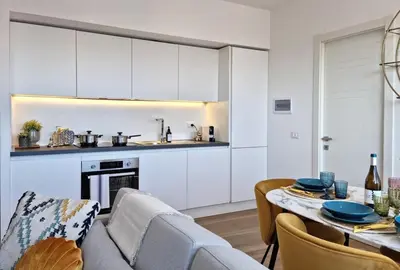 a kitchen and living room with white cabinets and a table at Attico Vacanza Roma Nord - Casa Mengotti in Rome