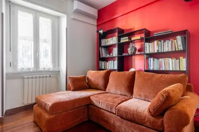 a brown couch in a room with a red wall at The Magic of San Peter in the Heart of Rome in Rome