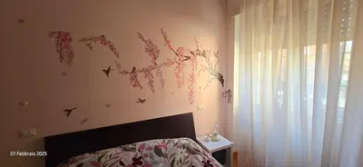 a bedroom with a bed with flowers on the wall at L'Oasi di Monteverde - grazioso e collegatissimo in Rome