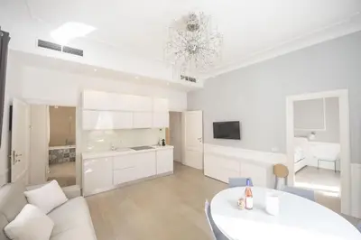 a white living room with a table and a kitchen at Saint Peter Beautiful 2BR Apartment in Rome