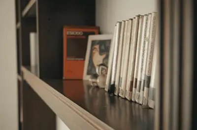 a row of books are lined up on a shelf at 10 Min Città del Vaticano-Stadio olimpico Lucia Apartment 1BDR in Rome