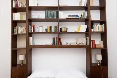 a book shelf above a bed in a bedroom at 10 Min Città del Vaticano-Stadio olimpico Lucia Apartment 1BDR in Rome