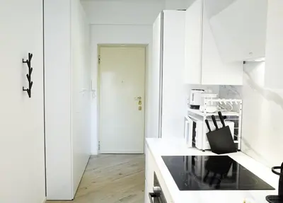 a kitchen with white cabinets and a black stove top oven at 10 Minuti Stazione Trastevere - Atelier 19 1BDR by Hôtea in Rome
