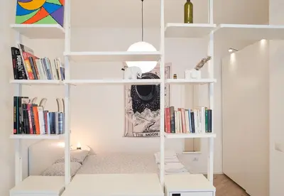 a room with white shelves with books at 10 Minuti Stazione Trastevere - Atelier 19 1BDR by Hôtea in Rome