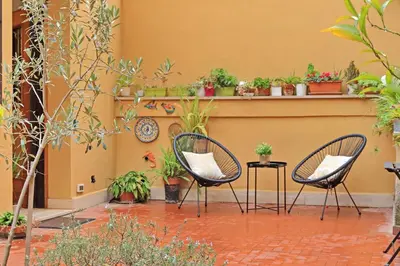 two chairs and a table in a courtyard with potted plants at La corte di San Paolo by DomusDimore in Rome