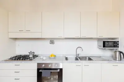 a white kitchen with white cabinets and a sink at HospitalityRome Doninzetti 20 in Rome