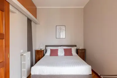 a bedroom with a bed with white sheets and red pillows at HospitalityRome Doninzetti 20 in Rome