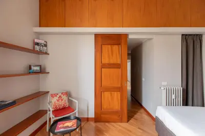 a bedroom with a bed and a chair and a door at HospitalityRome Doninzetti 20 in Rome