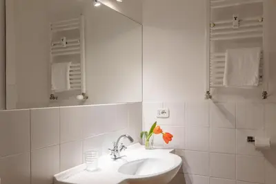 a white bathroom with a sink and a mirror at HospitalityRome Doninzetti 20 in Rome