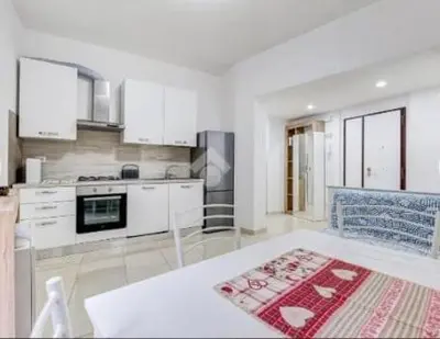 a large kitchen with white cabinets and a red rug at Casa Vulture in Rome