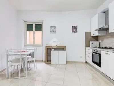 a white kitchen with a table and a table and chairs at Casa Vulture in Rome