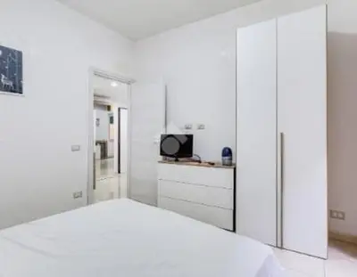 a white bedroom with a bed and a tv at Casa Vulture in Rome