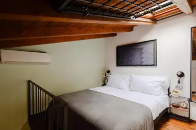 a bedroom with a white bed with a tv on the wall at Casa Piccinino in Rome