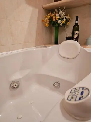 a white bath tub with a bottle of wine and flowers at Private SPA Apartment in Rome in Rome