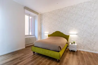 a bedroom with a green bed and a white wall at The Temple Apartment in Rome