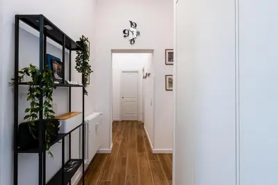a hallway with white walls and a black shelf with plants at The Temple Apartment in Rome
