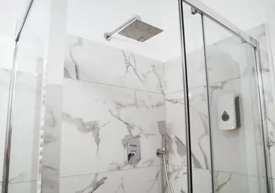 a bathroom with a shower with white marble at Thery House - Tiburtina Apartment in Rome
