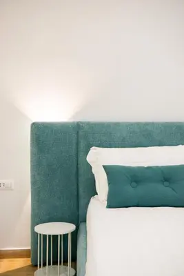 a bed with a green headboard and a table at Ventuno Dei Luxury Suites San Giovanni in Rome