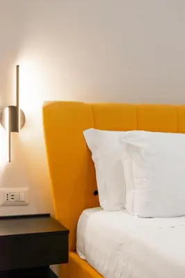a bed with an orange headboard and white pillows at Ventuno Dei Luxury Suites San Giovanni in Rome