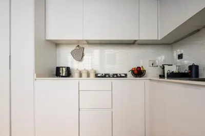 a white kitchen with white cabinets and appliances at Trastevere Luxury Studio in Rome