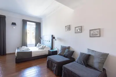 a bedroom with a bed and a couch and a chair at A Trastevere da M.E. in Rome