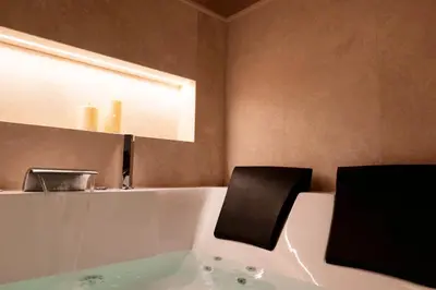 a bathroom with a tub with a black chair in it at HeySuite Classic - Luxury House - Navona in Rome