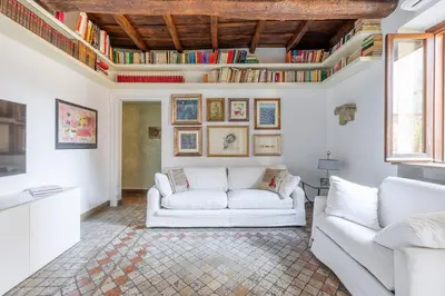 a living room with a white couch and books at NOSTROMONDO Prestigious 2 bedrooms Domus in Forum Area in Rome