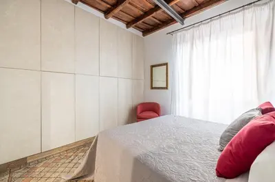 a bedroom with a bed and a red chair at NOSTROMONDO Prestigious 2 bedrooms Domus in Forum Area in Rome