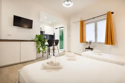 a white room with two beds and a kitchen at Domus Boccea - Vatican Apartment in Rome