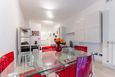a kitchen with a glass table and red chairs at Desiré Flat - Vatican City - Metro Cipro and WiFi in Rome