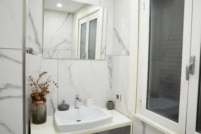 a white bathroom with a sink and a mirror at Roma Vaticano Deluxe Apartment in Rome