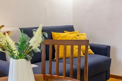 a blue couch with yellow pillows and a vase on a table at iFlat Colosseo Prestige in Rome