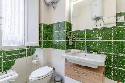 a bathroom with a sink and a toilet and green tiles at iFlat Colosseo Prestige in Rome