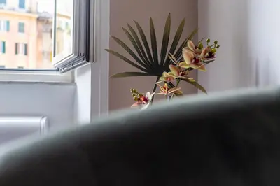 a vase of flowers sitting next to a window at iFlat Vatican Bright & Comfortable Apartment in Rome