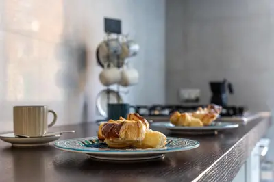 three plates of pastries on a counter with a cup of coffee at iFlat Vatican Bright & Comfortable Apartment in Rome