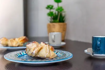a table with two plates of pastries and a cup of coffee at iFlat Vatican Bright & Comfortable Apartment in Rome