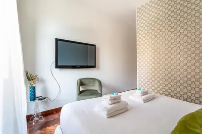 a room with a bed with a tv and a chair at iFlat Vatican Bright & Comfortable Apartment in Rome