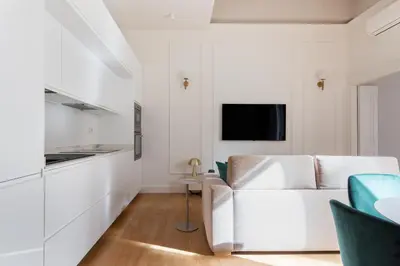 a white living room with a couch and a tv at Vittorio Emanuele Grand Apartment in Rome