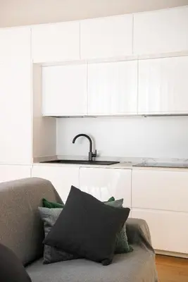a kitchen with white cabinets and a couch and a sink at Vittorio Emanuele Grand Apartment in Rome